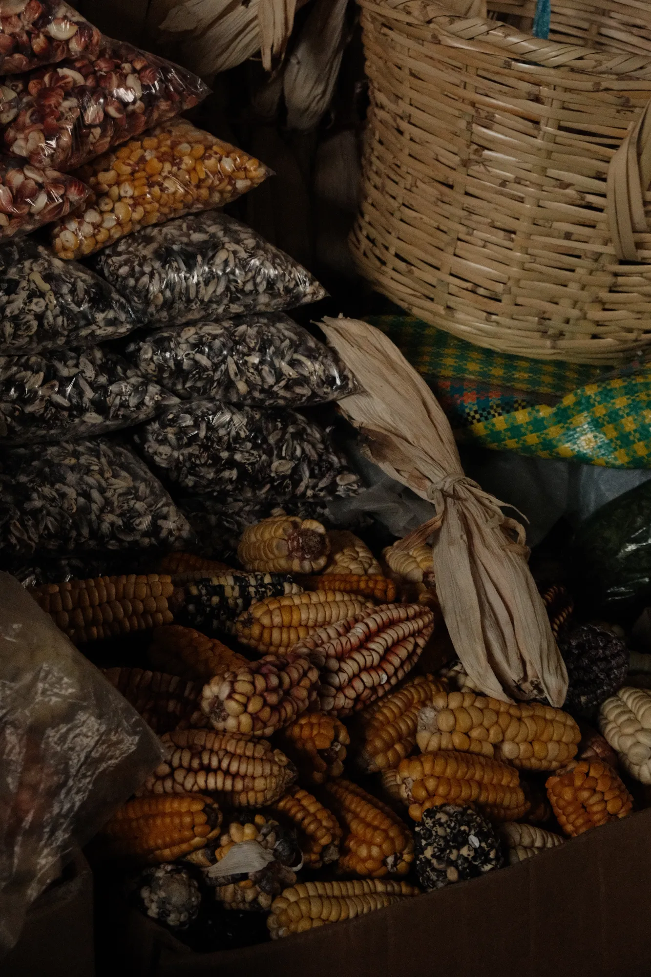 Dried corn, grains, and beans piled at the same Cusco market stall.