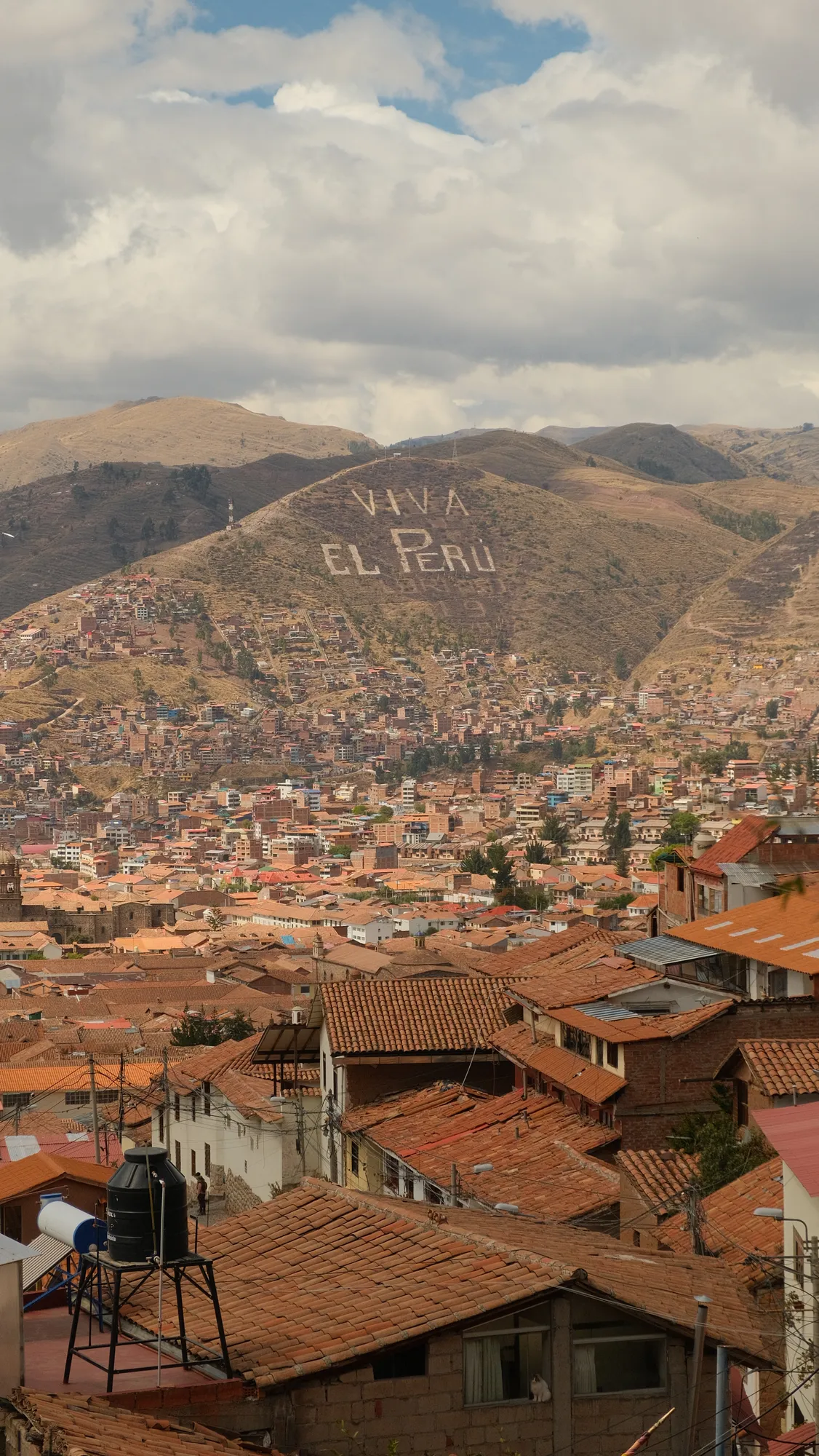 The words "Viva El Perú" spelled out on a hillside above Cusco, the old town's tiled roofs and cathedral below.