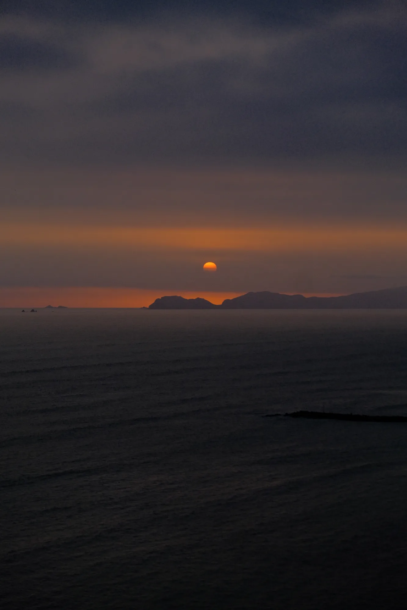 The sun sinks further behind the coastal cliffs south of Lima, its light softening across the water.