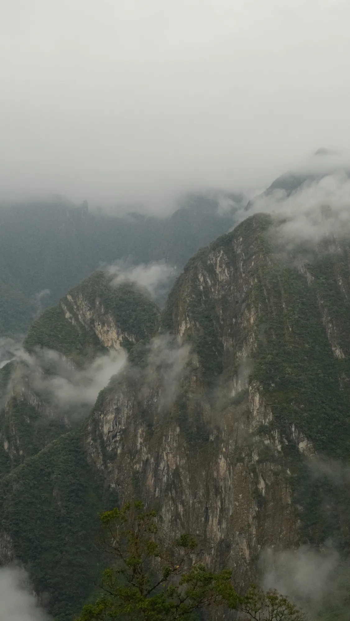 Clouds drift through steep, forested peaks above Machu Picchu in the early morning.