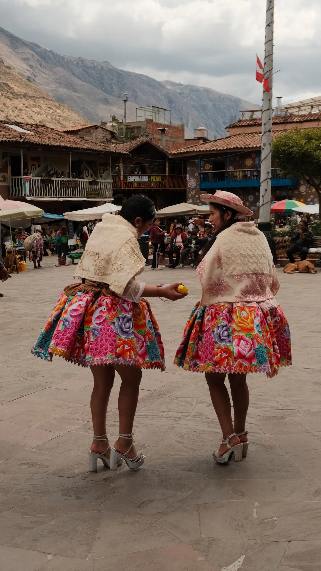 The bride and groom pause in the crowd outside the church in Pisac, bouquets of wildflowers in hand.