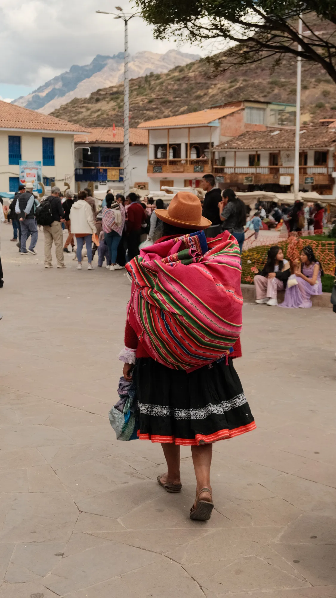 Wedding guests fill Pisac's plaza, market stalls and colonial buildings in the background.